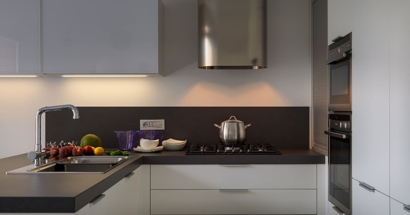 Modern U-shaped kitchen renovation Glen Waverley - handleless white cabinets, dark stone splashback, gas cooktop and cylindrical stainless steel rangehood
