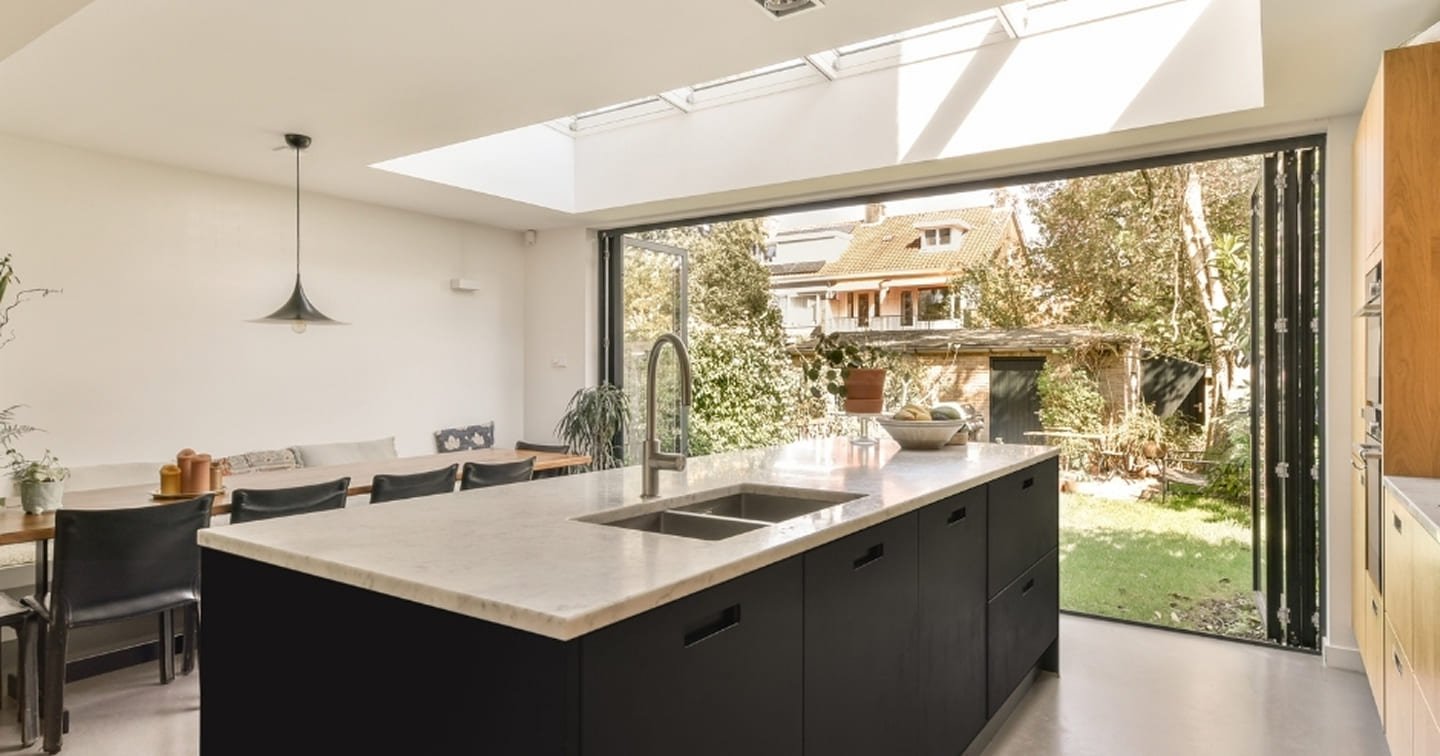 Modern rear extension Lilydale - dark kitchen island with stone benchtop, continuous skylight strip, bifold doors and polished concrete floor