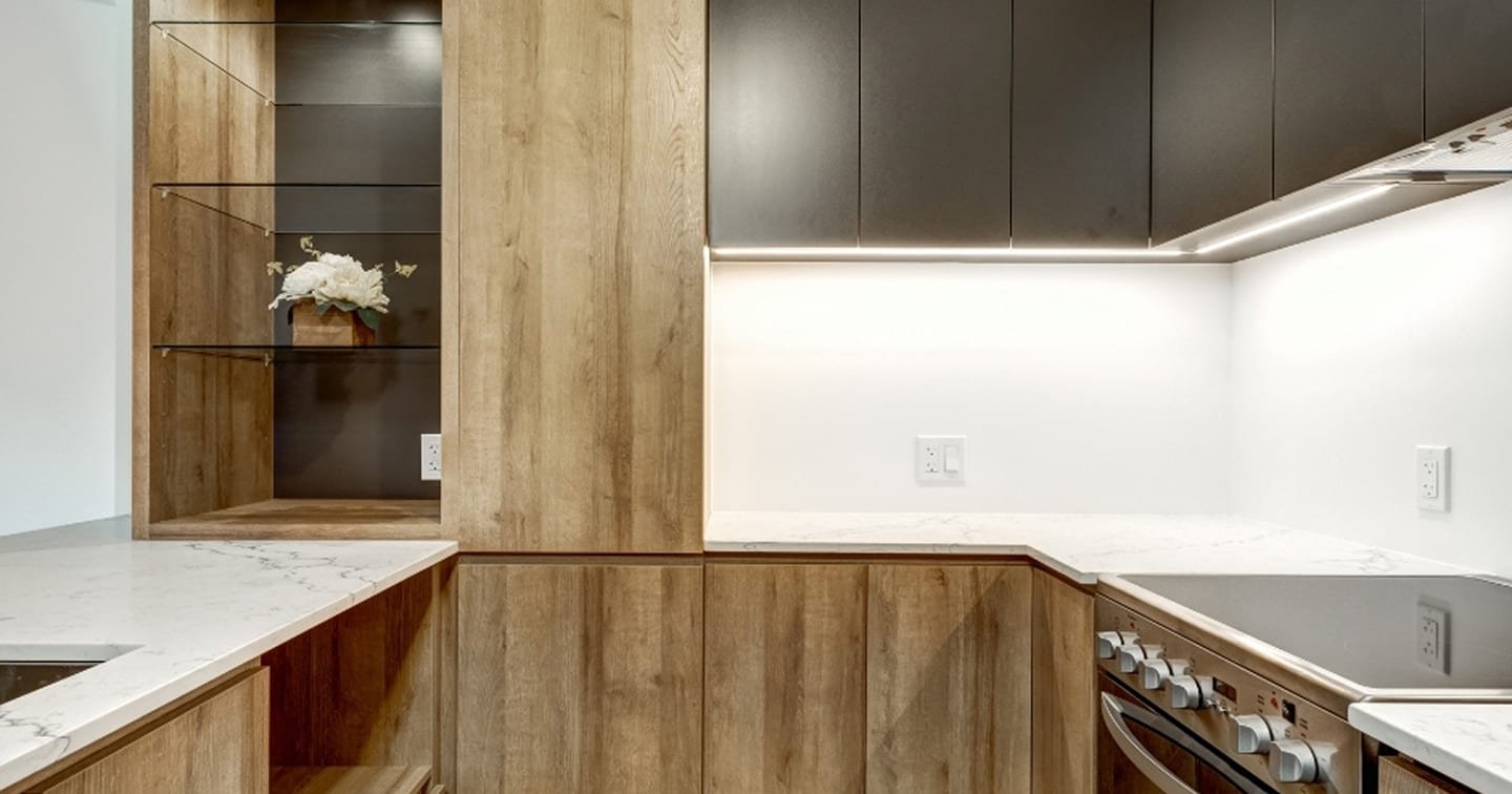 Two-tone kitchen renovation Nunawading - natural timber lower cabinets, dark matte overhead cabinets, marble-look benchtop, glass display cabinet and LED strip lighting